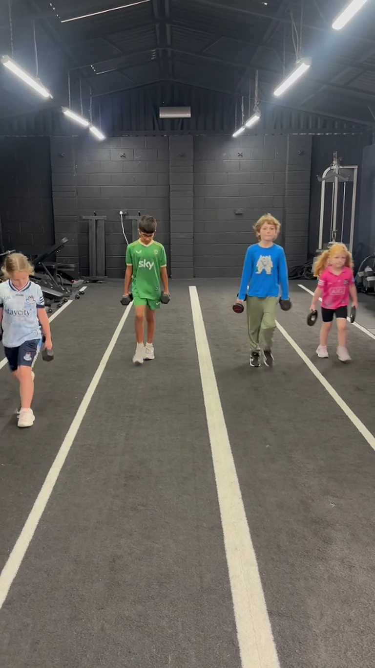 Loc'Down Youth group completing coached loaded carries in the indoor training lane